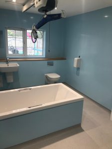 A bathroom with a harness, bath, toilet and sink