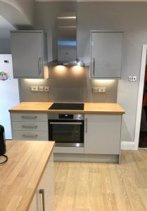 A kitchen with grey cabinets and wooden counter tops