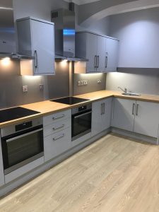 A kitchen with grey cabinets and wooden counter tops